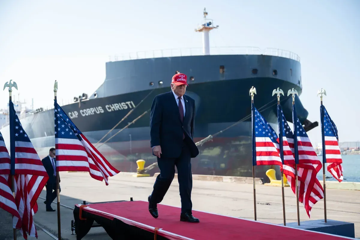 Donald Trump camina sobre una pasarela roja rodeado de banderas estadounidenses con un buque petrolero al fondo en el Puerto de Corpus Christi