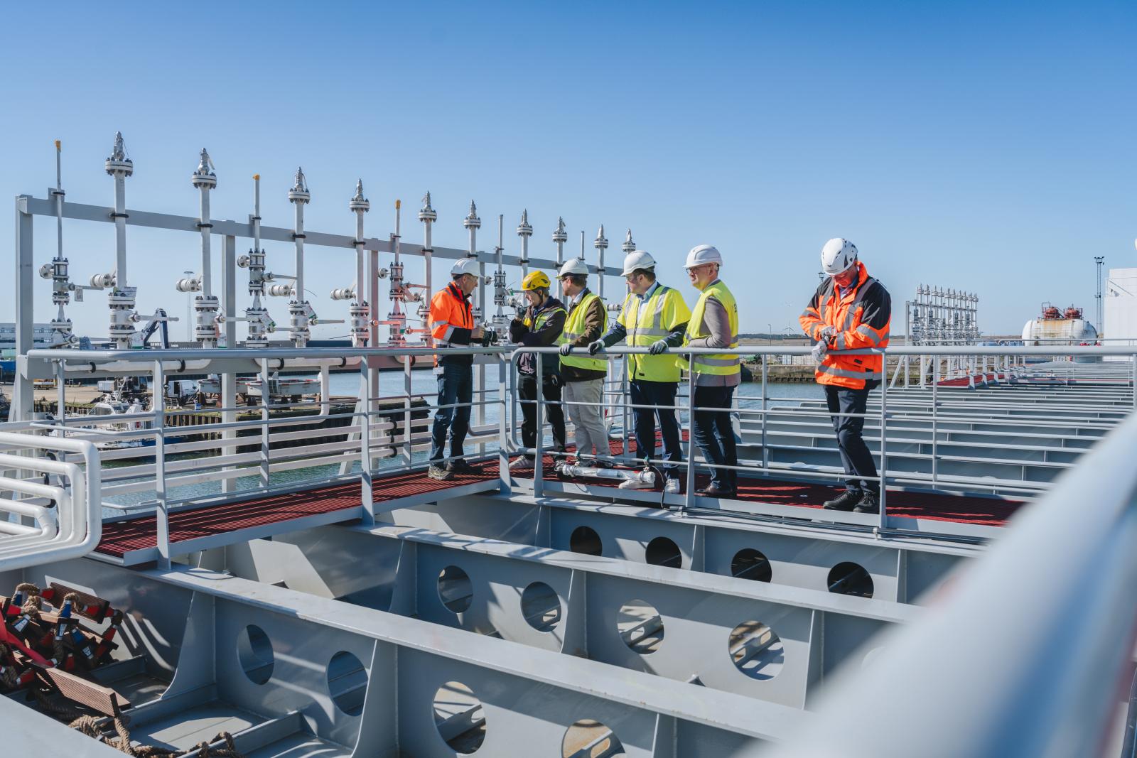 Grupo de visitantes con casco y chaleco de alta visibilidad a bordo del buque Carbon Destroyer 1, atracado en el puerto de Esbjerg (Dinamarca), durante una visita del proyecto Greensand