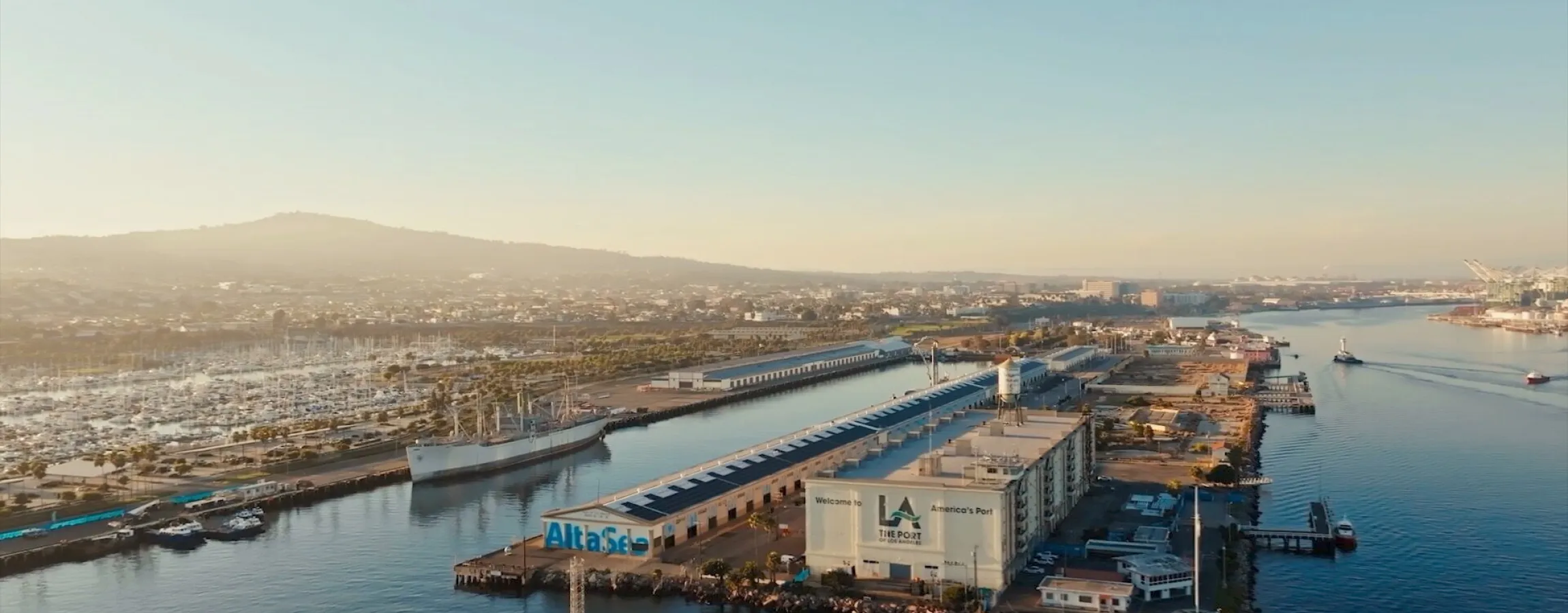 Vista aérea del campus de innovación AltaSea, en el puerto de Los Ángeles, con sus naves portuarias y embarcaderos junto al mar.